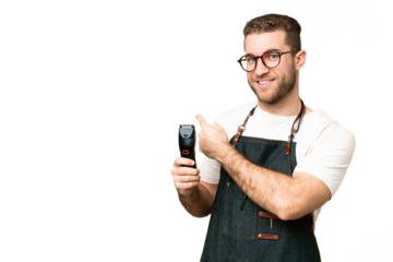 Barber man in an apron over isolated chroma key background pointing back