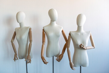Three mannequins posed against a wall.