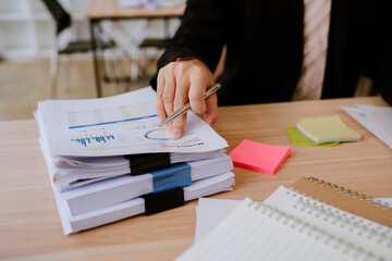 .Asian businessman checking documents. Asian man's hands meticulously check a stack of documents,...