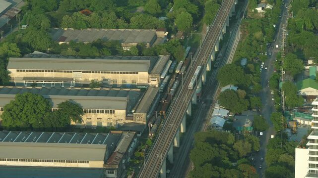 Aerial View of Skytrain Moving Through Urban Area in Thailand at Sunset