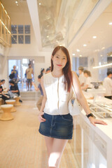 A woman in a white shirt and blue skirt poses for a picture in a restaurant