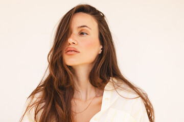 Enchanting brunette girl in casual white and yellow shirt standing on light background. Romantic...