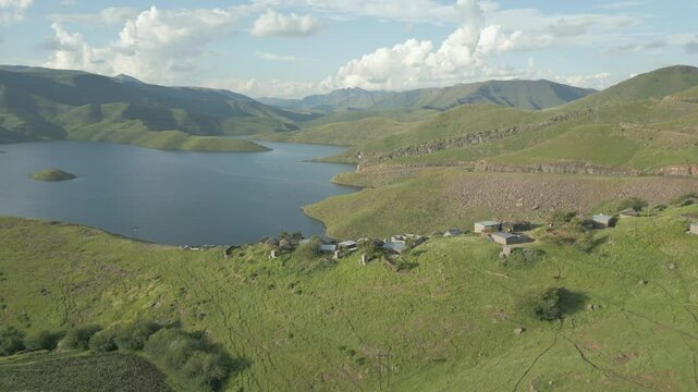 Flight over rural village in Lesotho reveals massive Mohale Dam reservoir between hills in background