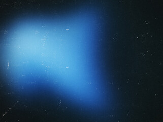 Obraz premium Blurred blue spot on a black background with dust, noise, and scratches. Perfect for use as an overlay texture or in various graphic design projects.