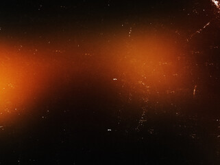 Abstract red-orange blurred light with dust, noise and scratches on a dark background. Ideal for use as an overlay effect or in various creative design projects.