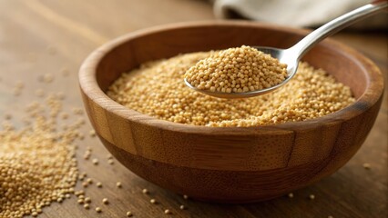 Close up view of raw amaranth grains in a wooden bowl with a spoon