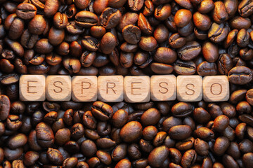 Wooden letters spell 'espresso' on roasted coffee beans background
