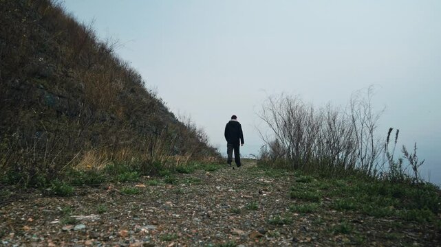 A man of European appearance walks near a mothballed solid waste dump. The concept of environmental conservation and safe disposal of waste