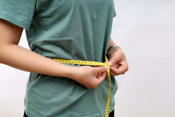 Close up woman in green t-shirt measuring her waist with yellow measuring tape. Weight loss, slim body, healthy lifestyle concept. Figure control and counting calories. Successful diet plan.