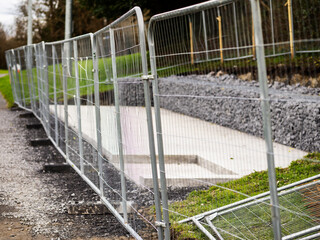 Metal fence blocking small construction site area in a park. Building sitting or barbeque area. Improve and upgrade. Sport observation point.