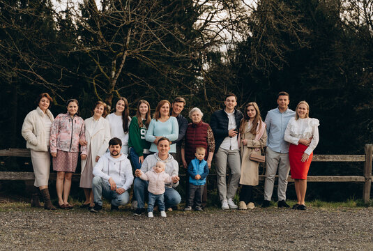A group of family members pose together in a park or garden, creating a warm, relaxed composition. The photo conveys emotions of closeness, togetherness, family traditions and moments of unity.