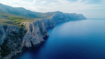 Fototapeta premium Aerial view of dramatic coastal cliffs meeting a deep blue sea under a partly cloudy sky, showcasing rugged terrain and tranquil waters. : Generative AI