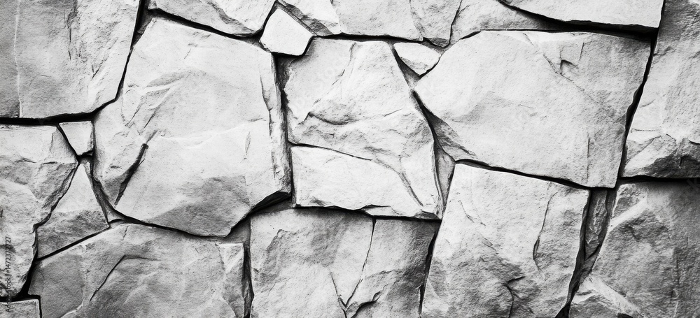 Leinwandbilder a grayscale image showcasing a rugged, textured stone wall, composed of irregularly shaped, gray sto