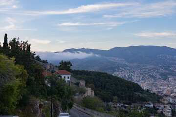 Urban landscape with mountain backdrop, mist, and historical architecture. Ideal place for tourism and sunset photography.