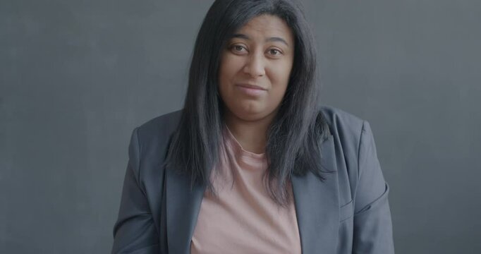 Slow motion portrait of unhappy young woman showing thumbs-down hand gesture on black color background. Negative emotion and people concept.