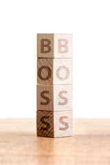 Stacked Wooden Cubes with Letters Spelling the Word Boss on a Wooden Table