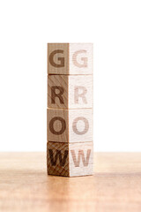 Stacked wooden blocks spell grow, depicting the theme of personal development and progress in a...