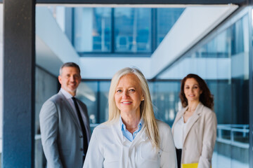 Professional female physician standing confidently with medical team, showcasing collaborative healthcare leadership in contemporary clinical setting