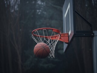 Fototapeta premium A basketball is about to swish through the hoop, illuminating the dark and moody surroundings.