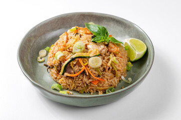 Khao Pad Pet dish with rice, vegetables, chicken and basil, served in a green ceramic bowl on a white background. Bright and inviting photo, perfect for traditional Thai and Asian cuisine themes.