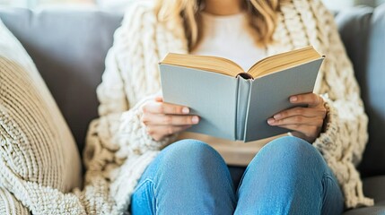A cozy scene featuring a close-up of a woman’s hand holding a cup, with her other hand resting on an open book.