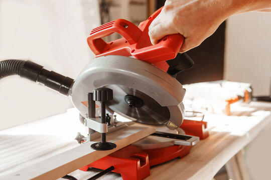 Circular saw in action as a carpenter skillfully cuts wooden planks. Hands hold the wood against the saw, showcasing precision and craftsmanship in woodworking