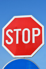 A red octagonal stop sign with white lettering stands against a clear blue sky