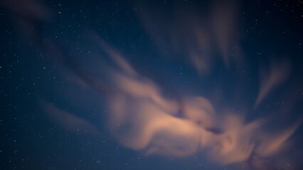 Fototapeta premium A mesmerizing twilight sky showcases a breathtaking display of vibrant orange clouds gently swirling amidst a tapestry of twinkling stars offering a serene and peaceful nocturnal landscape.