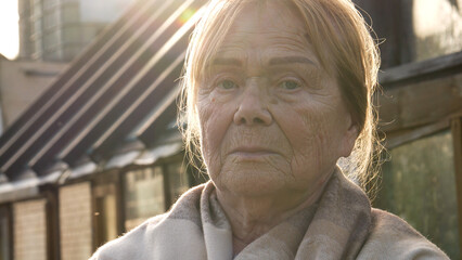 Elderly woman with blonde hair and deep wrinkles on skin is posing with neutral expression on face....