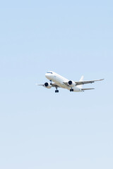 Airplane descends towards the runway on a clear day, showcasing its undercarriage and landing gear.