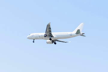 Airplane descends towards the runway on a clear day, showcasing its undercarriage and landing gear