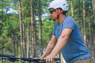 Short Respite: A portrait of a sport hobbyist that has stopped their ride and resting amongst the pine trees of an urban park. This photo is part of a series that highlights themes of healthy living.