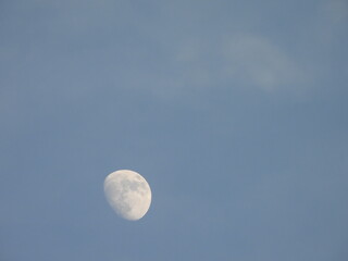 Daytime moon, visible in blue sky, above the Bombay hook National Wildlife Refuge, Kent County,...