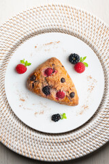 Triangular English scones with blackberries, raspberries and chocolate chips. Top view table with christmas decorations.