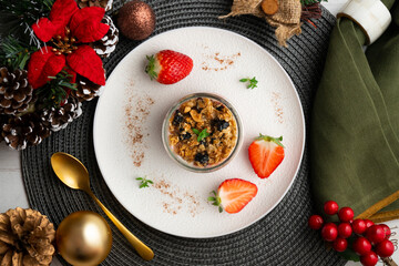 Greek yogurt with strawberries and granola made with cereals and nuts. Top view table with christmas decorations.