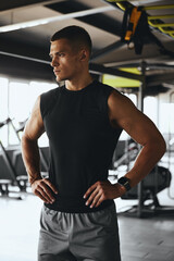 Fit tired caucasian man breathing while taking a break from workout, training or exercising inside a fitness gym. Young athletic, masculine guy resting after his strength or muscle exercise session.