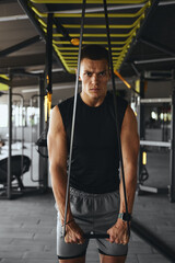Handsome toned man in activewear is executing a warm up workout with a resistance band, focusing on...