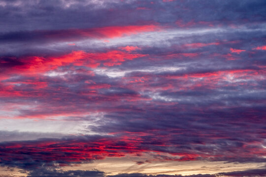 Intense red and violet clouds during sunset over horizon, offering dynamic color blend and visual impact for editorial, nature, or conceptual background compositions.