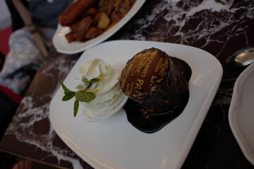 Decadent chocolate dessert with whipped cream and mint on marble surface in elegant dining setting
