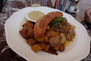 Delicious sausage dish served with roasted potatoes and savory sauerkraut on a classic plate in a cozy setting