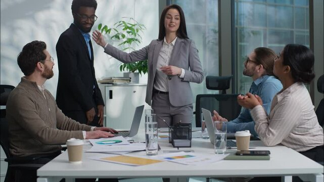 Caucasian businesswoman woman HR manager leader inviting African American businessman man new worker employee hire welcoming friendly team cheering applause office multiethnic business people company