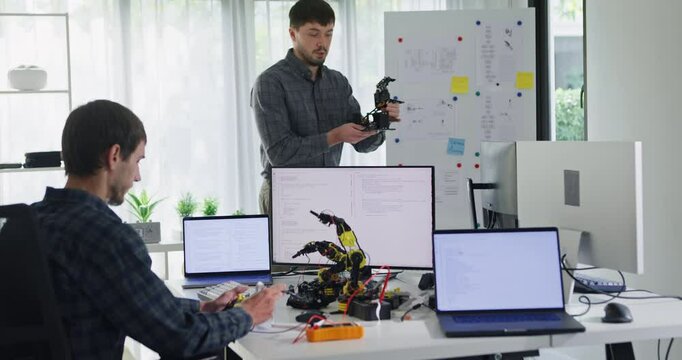 Team adult male engineer develop present AI robotics hand project at tech workspace. Artificial intelligence, collaboration support prototype development, robotic, debugging, machine learn, training.