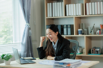 A young entrepreneur celebrates a business win at her desk, smiling with excitement as she looks at her laptop — capturing the energy of success and achievement in the startup world.