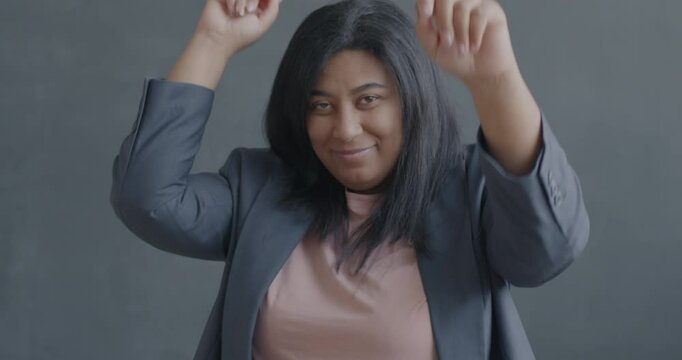 Slow motion portrait of happy young woman dancing smiling moving hands looking at camera on black color background. People and fun concept.