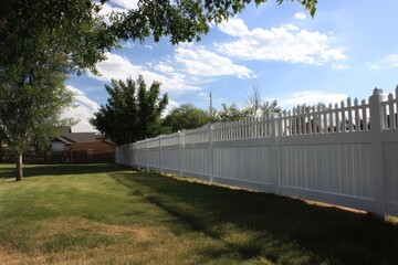 Contemporary White Vinyl Fence with Lush Green Grass and Clear Blue Sky in Modern Yard