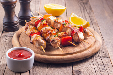 Delicious grilled chicken skewers with capsicum, lemon, salad and ketchup on a plate over the table. Chicken kebab. Healthy food concept.