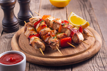 Delicious grilled chicken skewers with capsicum, lemon, salad and ketchup on a plate over the table. Chicken kebab. Healthy food concept.