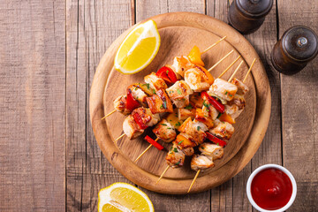 Delicious grilled chicken skewers with capsicum, lemon, salad and ketchup on a plate over the table. Chicken kebab. Healthy food concept.