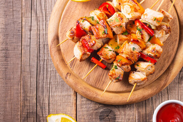 Delicious grilled chicken skewers with capsicum, lemon, salad and ketchup on a plate over the table. Chicken kebab. Healthy food concept.