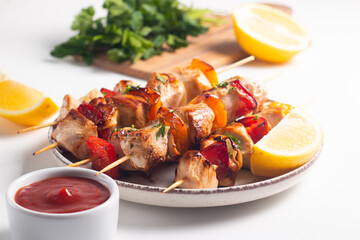 Delicious grilled chicken skewers with capsicum, lemon, salad and ketchup on a plate over the table. Chicken kebab. Healthy food concept.